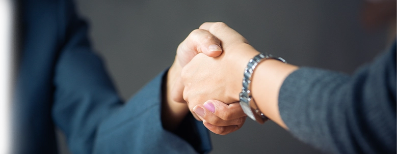 Close-up of two business professionals sealing a partnership with a firm handshake in an office setting.